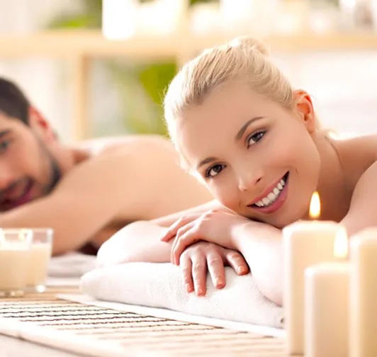 Couple relaxing side by side on massage tables by candlelight