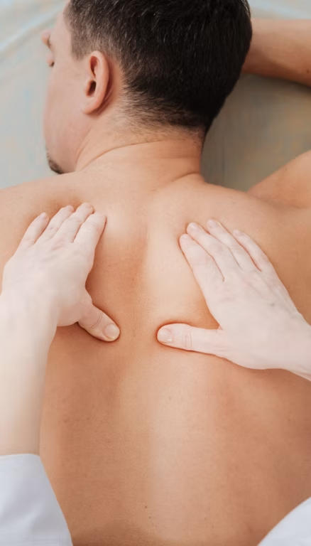 Therapist's hands working across a guest's upper back